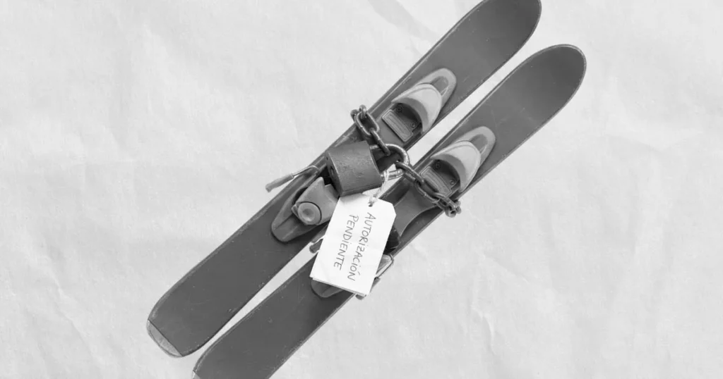 Esquíes atados con una cadena y un candado, con una etiqueta que dice “Autorización pendiente”.